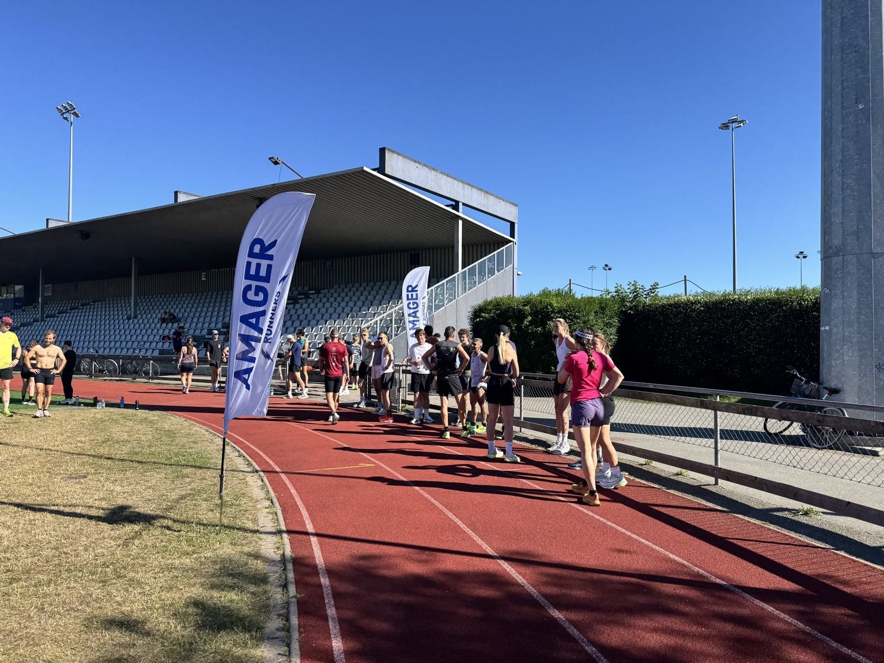 Amager Runners samles ved klubbens flag på banen i Sundby Idrætspark